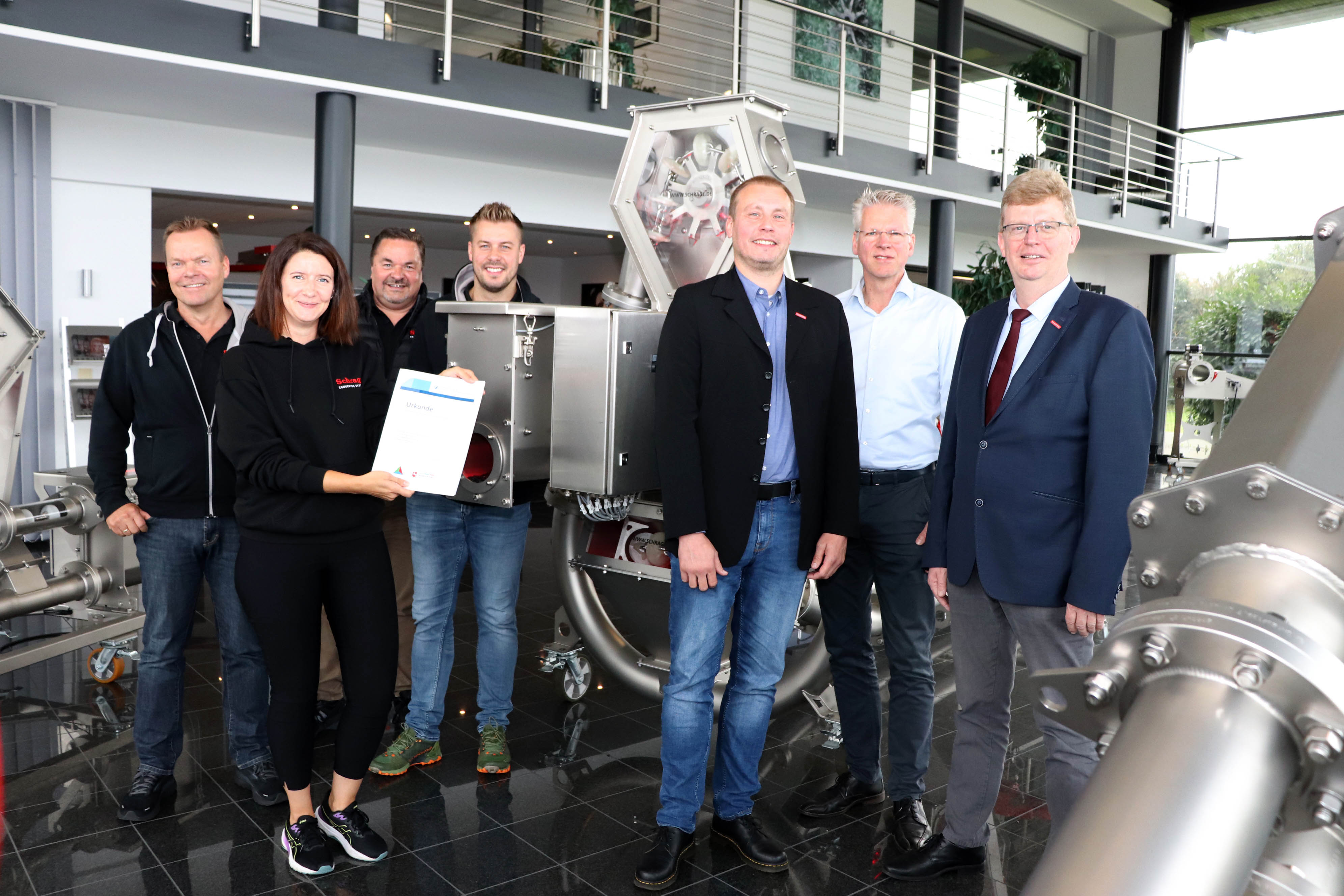 Geschäftsführer Frank (l.) und Ralf Schrage (3.v.l.) sowie Sohn Daniel Schrage (4.v.l.) und Projektleiterin Lena Bashagen (vorne). Es gratulieren (von rechts) von der Handwerkskammer Präsident Albert Lienemann, Thomas Harms und Michael Sandmann (HWK OL). 