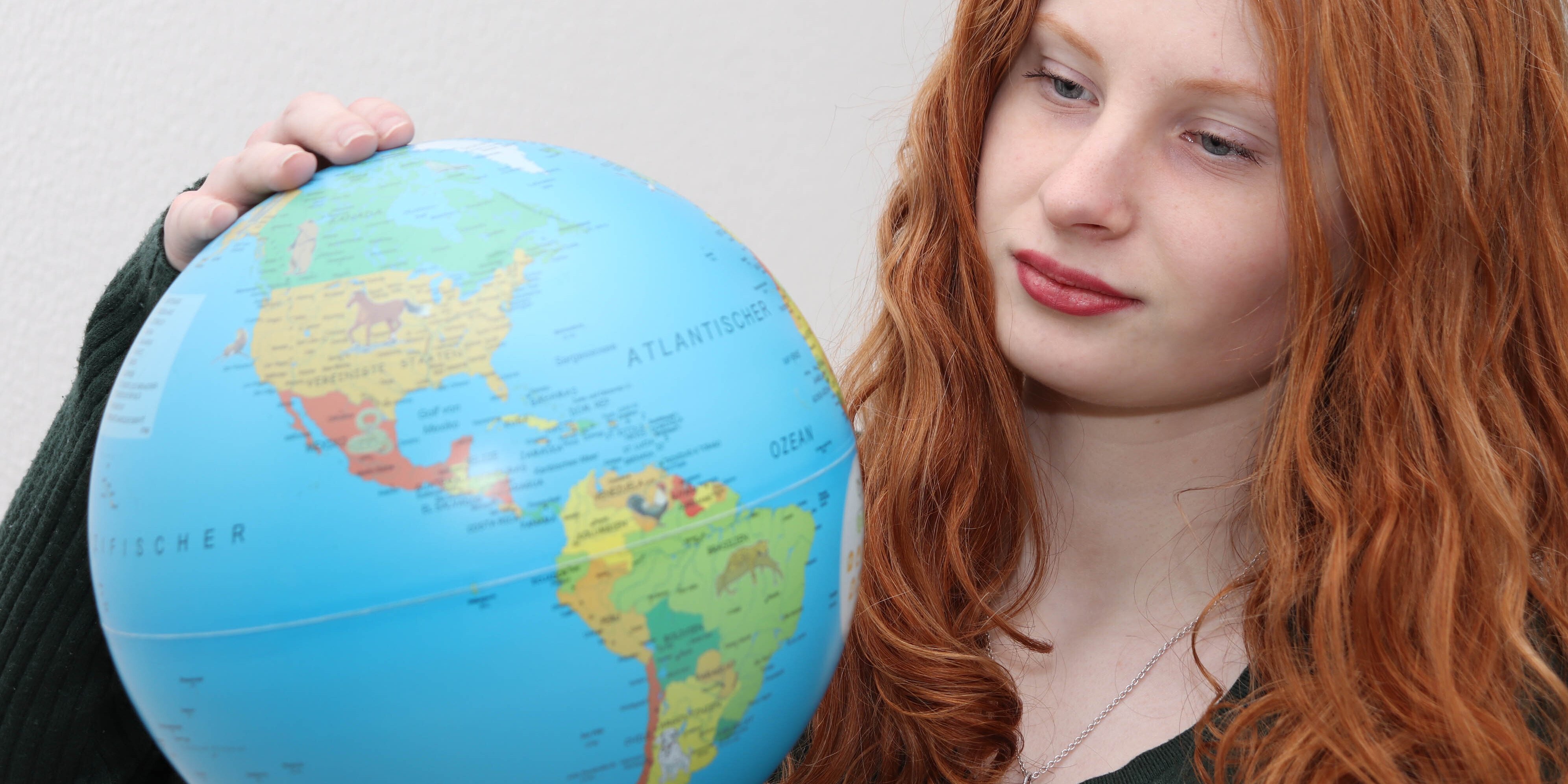 Ein Mädchen, hält einen Globus in der Hand.