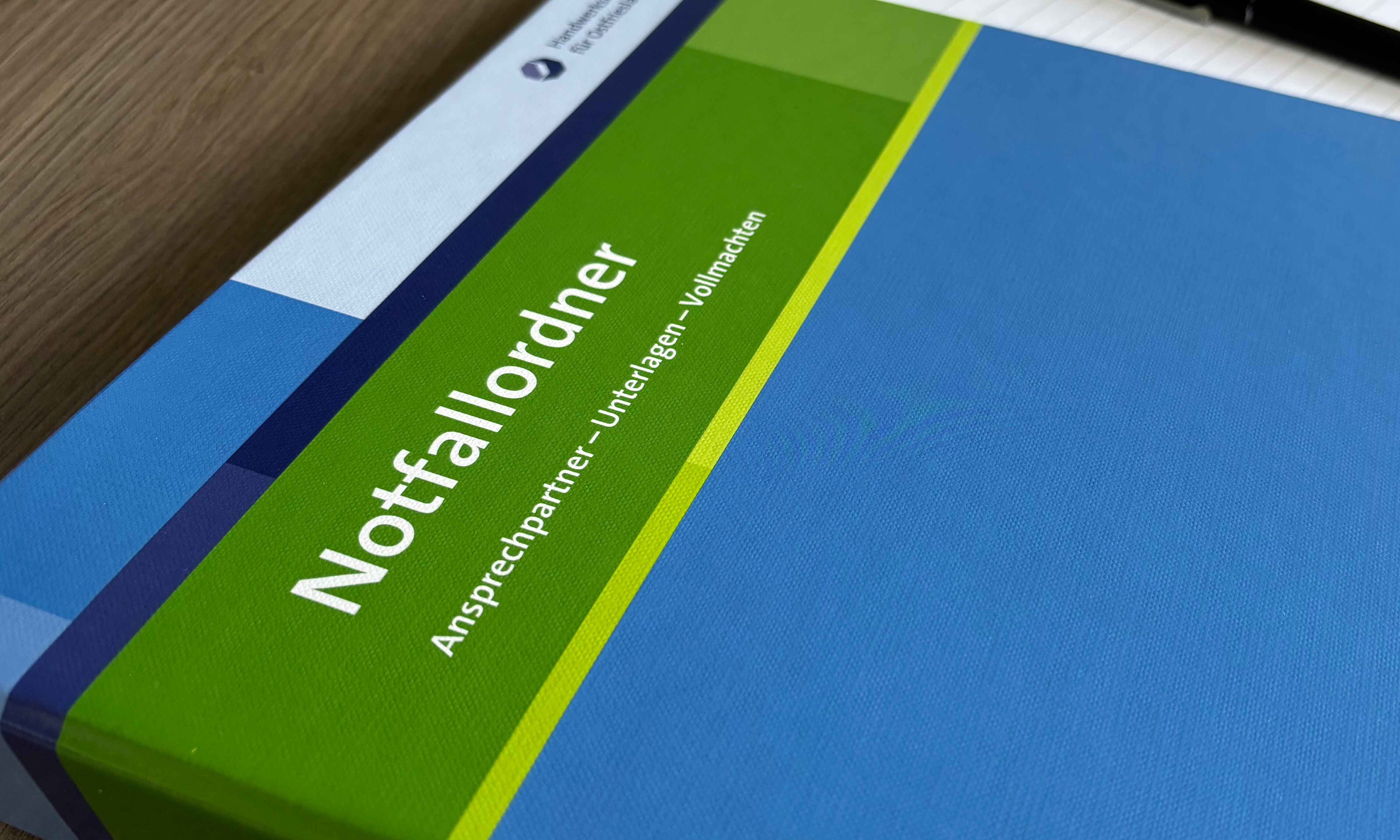 KI generiert: Das Bild zeigt einen Notfallordner mit der Aufschrift "Ansprechpartner - Unterlagen - Vollmachten" auf einem Tisch.