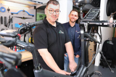Sascha Spies arbeitet an einem Farhrrad. Julian Berghem schaut ihm dabei zu.