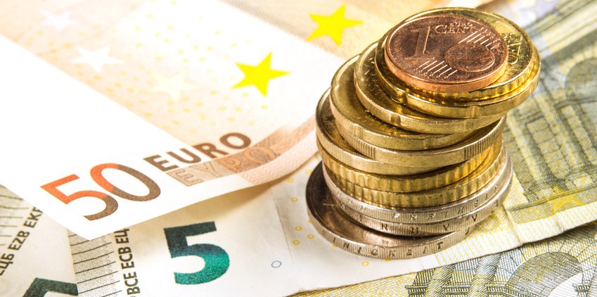 Ein Stapel Geldscheine und ein kleiner Haufen Münzen, symbolisch für finanzielle Mittel