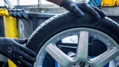 Hände halten einen Autoreifen.