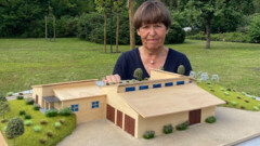 Eine Frau hält ein Gebäudemodell aus Holz.