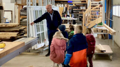 KI generiert: Ein Mann zeigt einer Gruppe von Kindern eine Werkstatt mit Holzarbeiten.