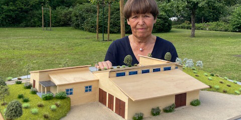 Eine Frau hält ein Gebäudemodell aus Holz.