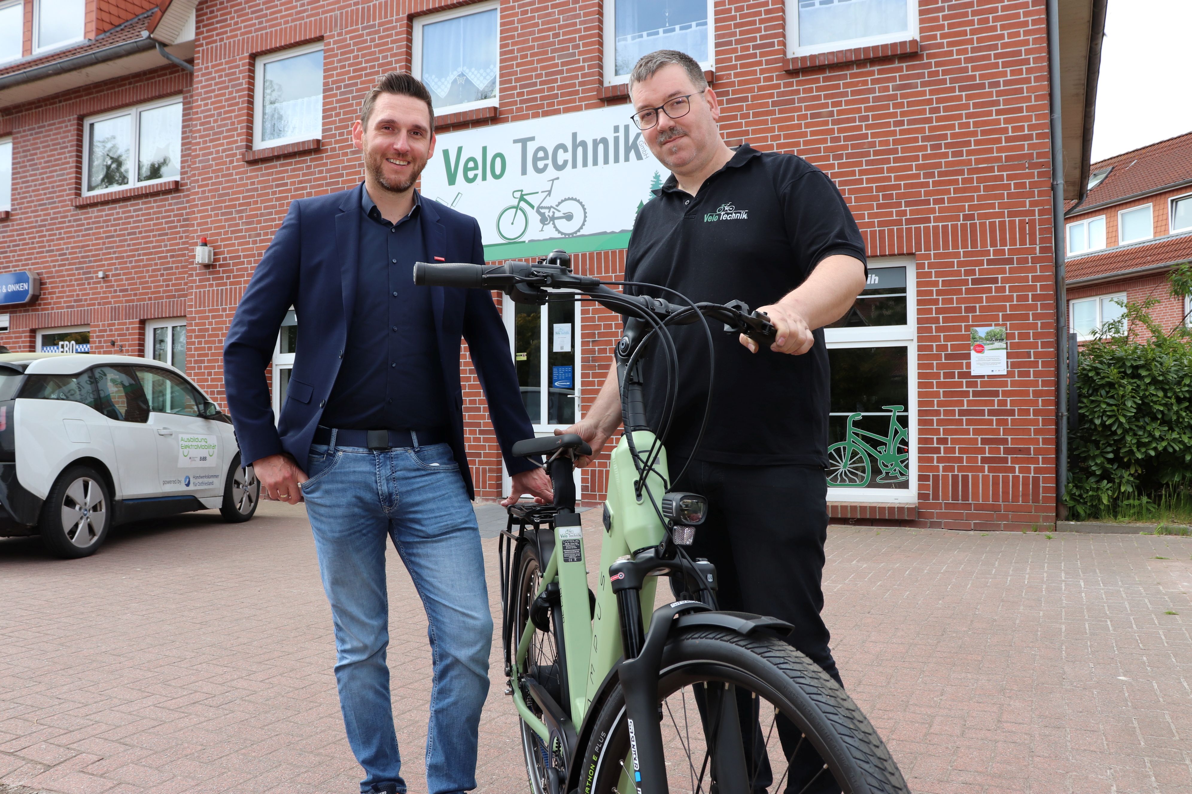 Meister Sascha Spies vor seinem Zweiradshop Velo Technik in Großefehn mit Betriebsberater Julian Berghem