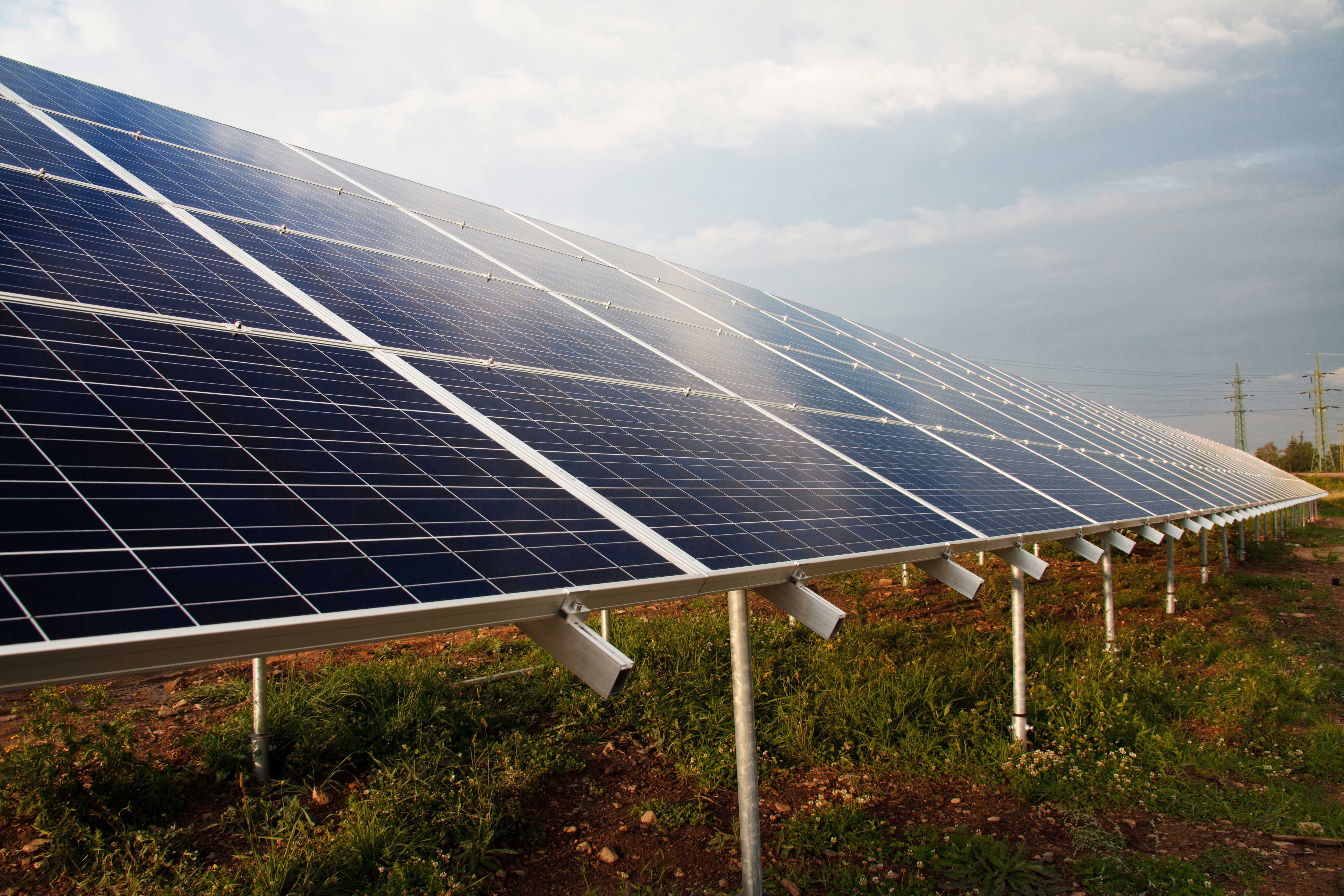 KI generiert: Das Bild zeigt eine Reihe von Solarmodulen auf freiem Feld, die zur Energieerzeugung genutzt werden.