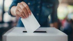 KI generiert: Eine Person steckt einen Stimmzettel in eine Wahlurne.