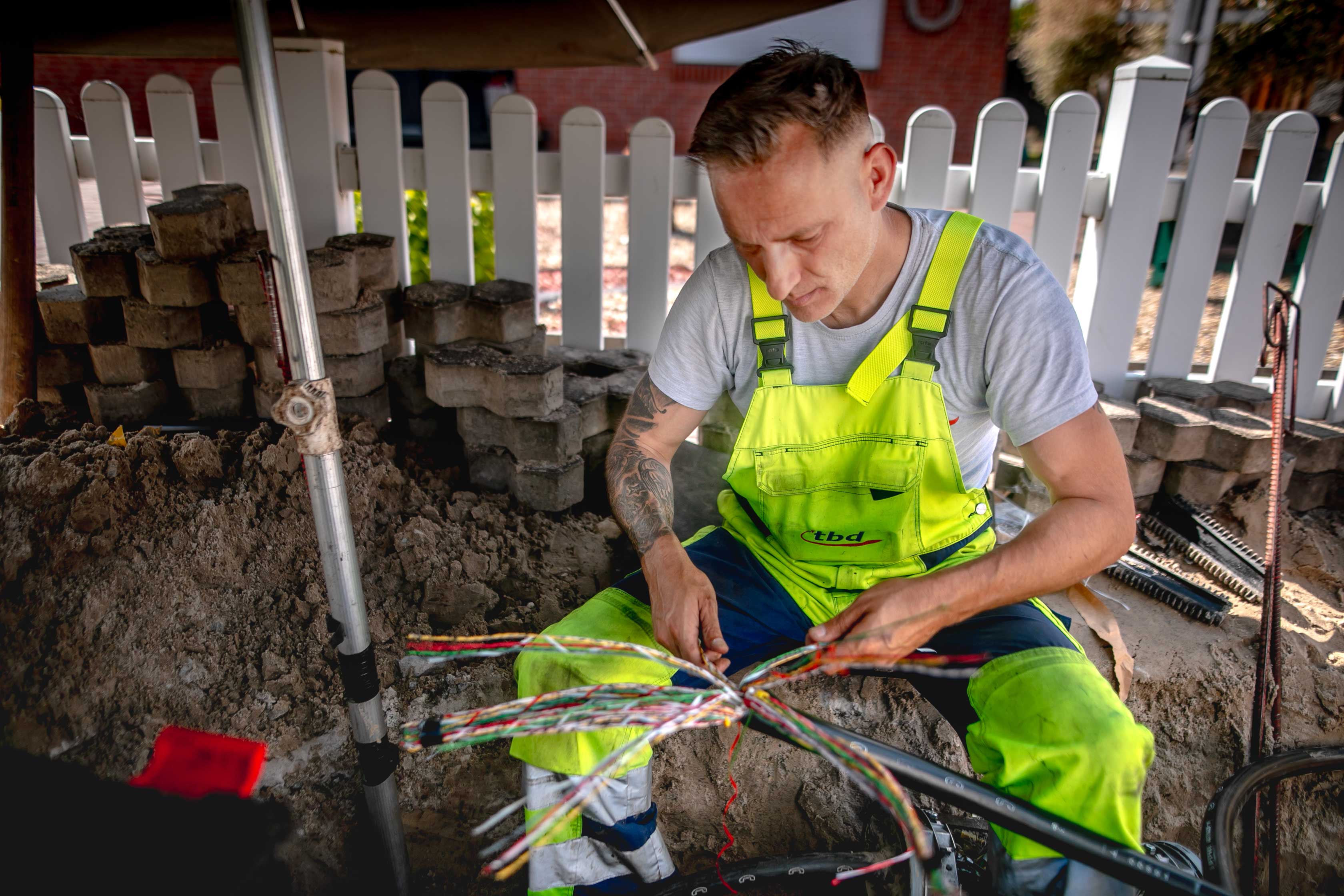Ein Monteur repariert ein Kupferkabel und spleißt dafür die Kabelader für den Bau einer Muffe.