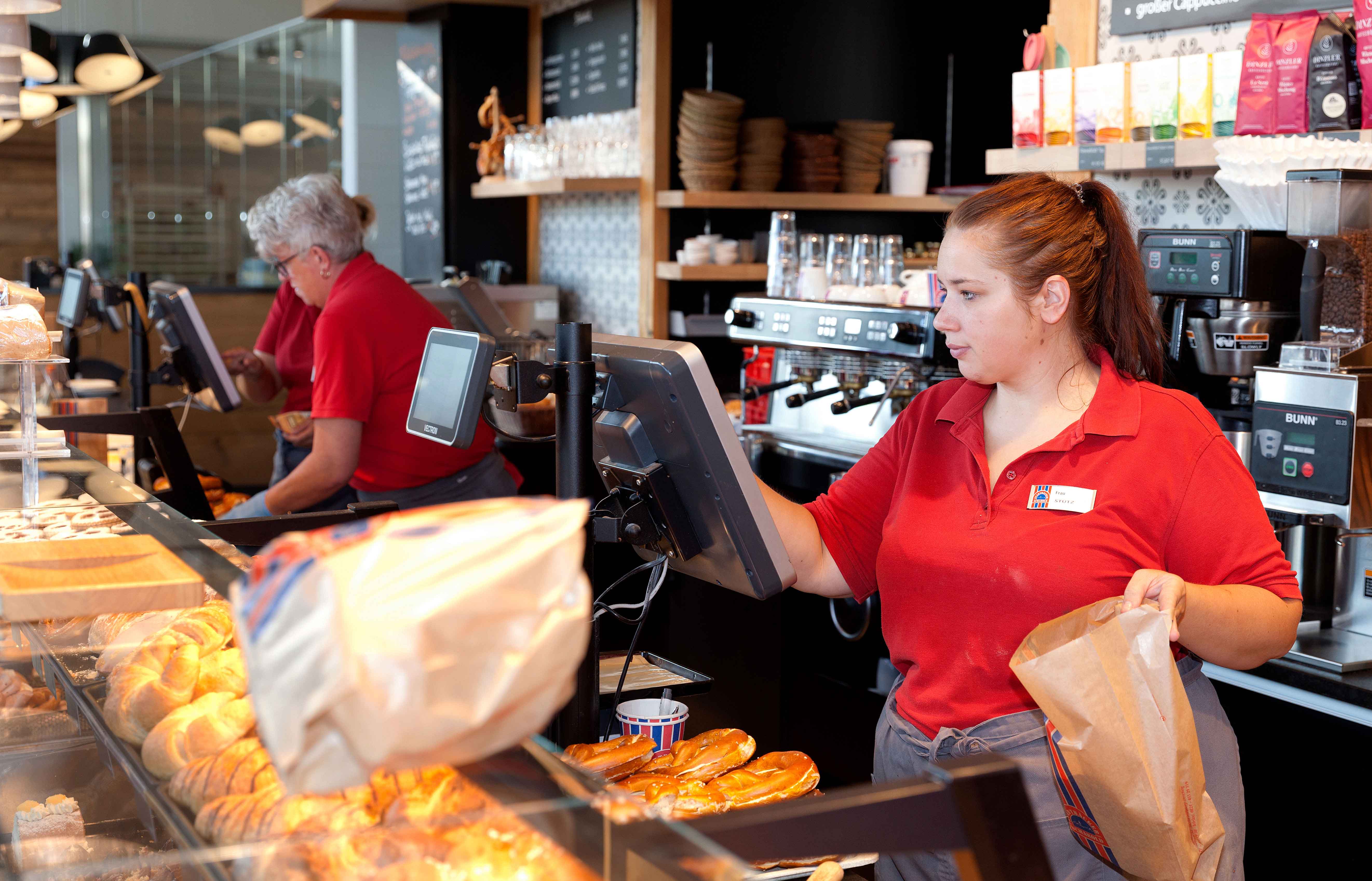 Zwei Frauen die in einer Bäckerei Brötchen verkaufen.
