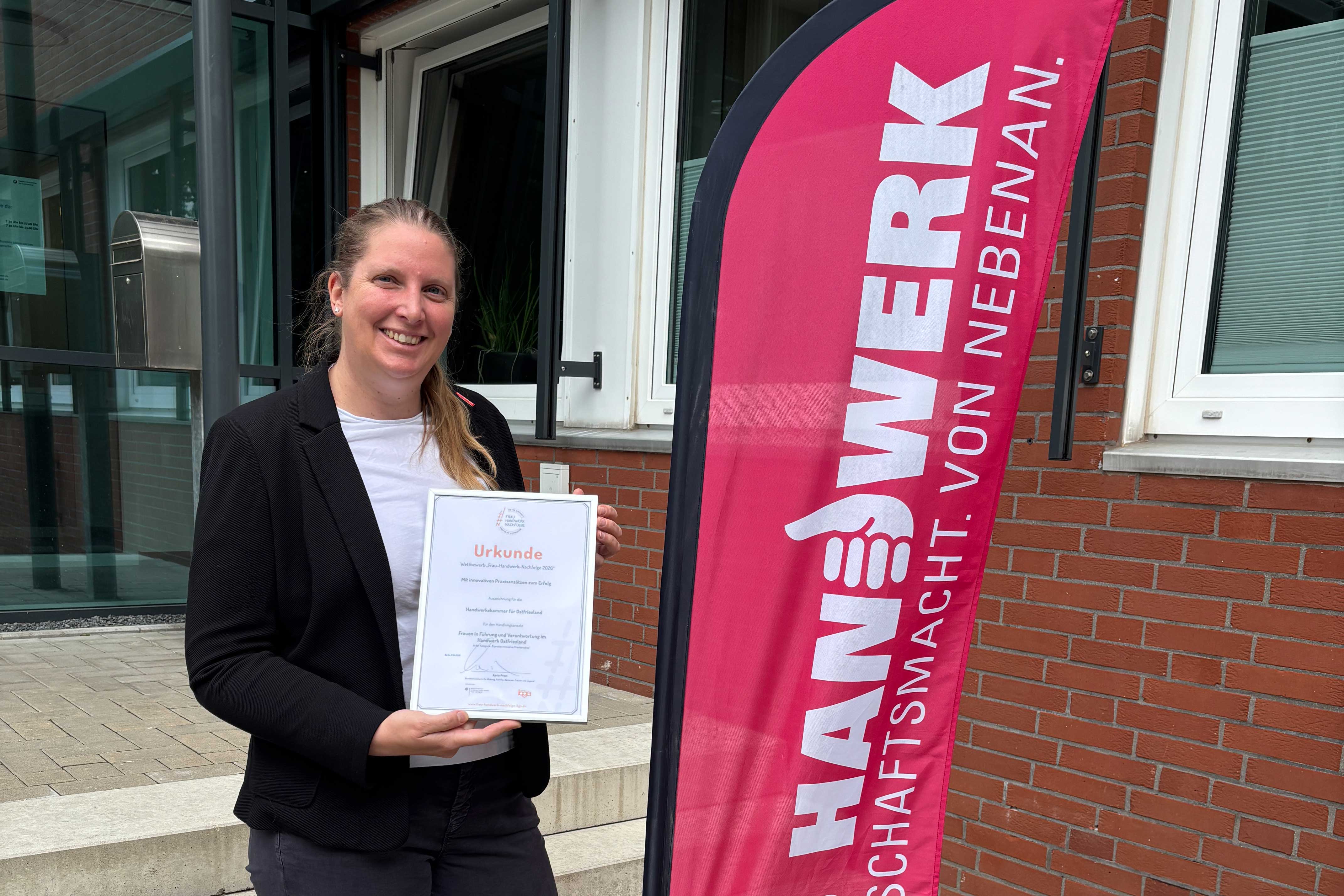 KI generiert: Eine Person steht lächelnd draußen und hält eine Urkunde in der Hand, während sie vor einem Werbebanner mit der Aufschrift "Handwerk" steht.