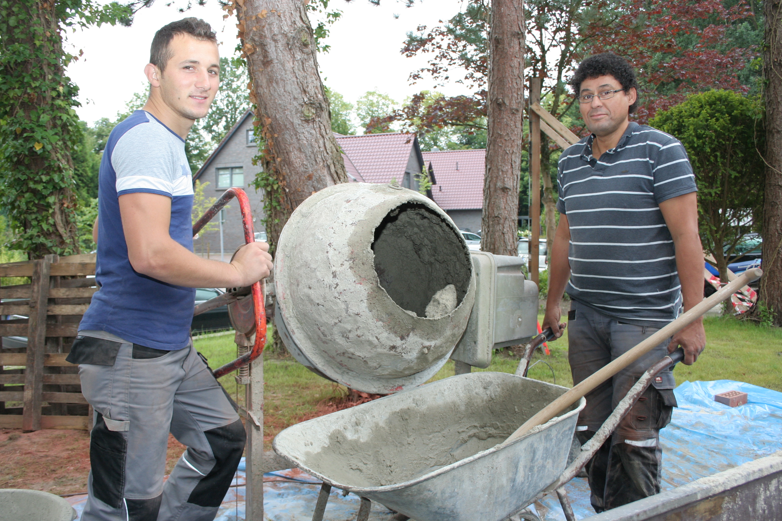 Mit einer Mischmaschine stellen zwei Handwerker frischen Beton her – bereit für den nächsten Arbeitsschritt.