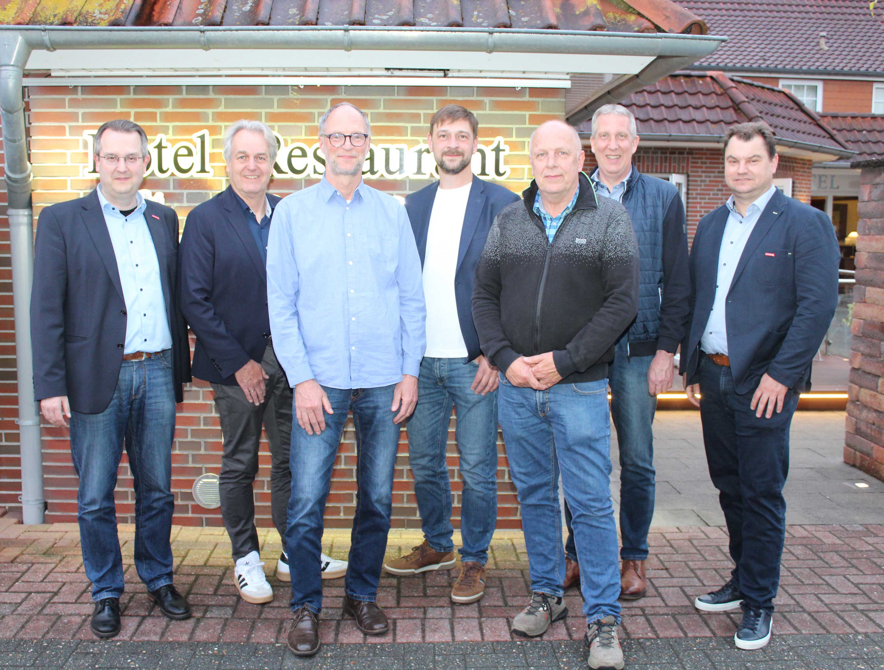 KI generiert: Eine Gruppe von sieben Männern steht vor einem Gebäude mit der Beschriftung "Hotel Restaurant".