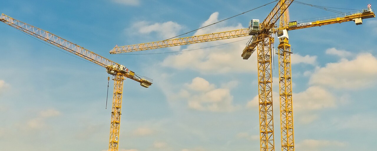 Drei große Kräne stehen auf einem Bau.