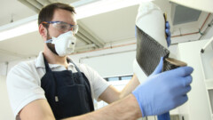 Ein Ortohpödietechniker arbeitetn mit Schutzmaske an einer Prothese.