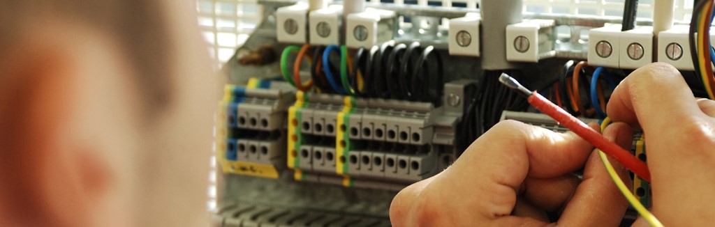 Fachkräfte ausbilden Ein Handwerker arbeitet an einem Stromkasten, er hlt ein Kabel und einen Schraubenzieher in der Hand.