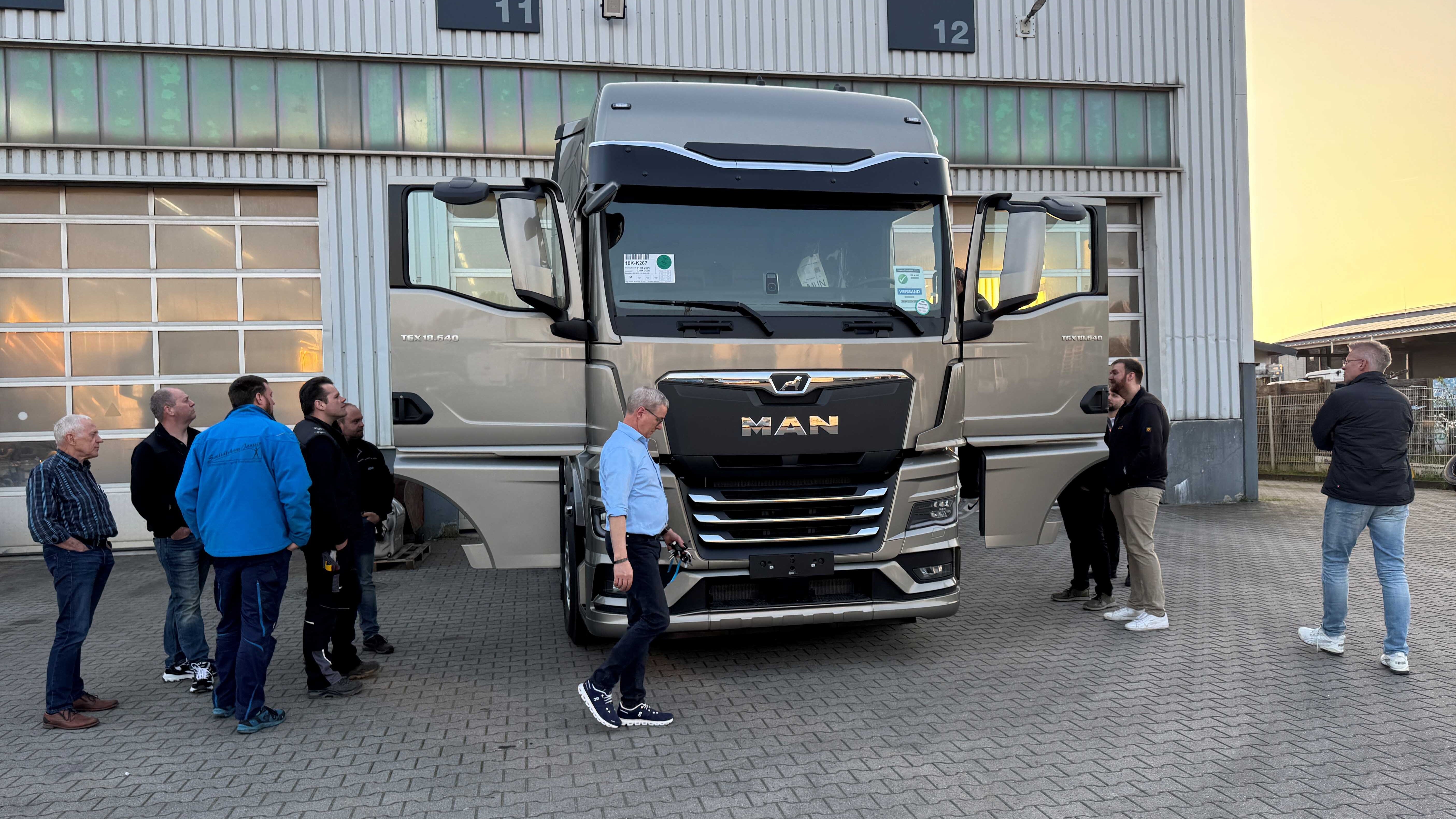 KI generiert: Menschen versammeln sich um einen MAN-Lkw vor einem Gebäude mit offenen Türen.