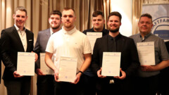 Sechs frisch ausgelernte Kfz-Mechatroniker halten stolz ihre Urkunden für das Foto fest.