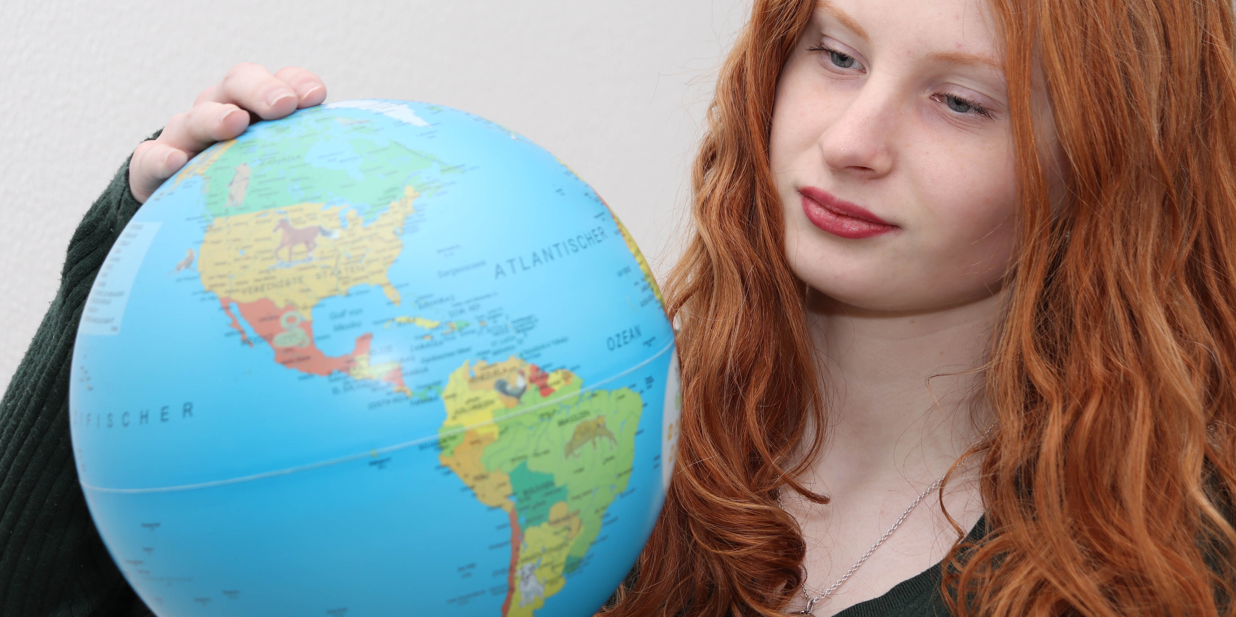 Ein Mädchen hält einen Globus in der Hand.